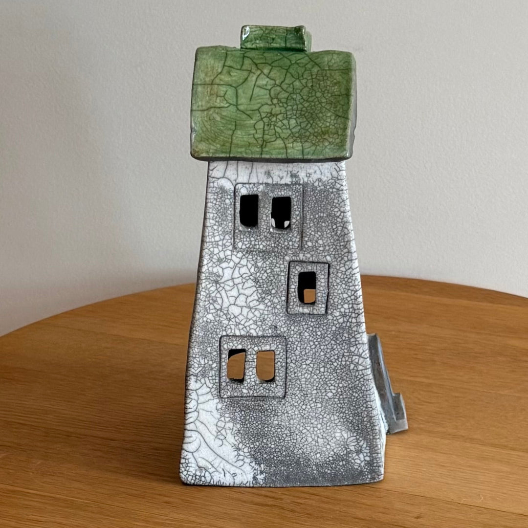 Ceramic tall tealight house with green roof on a wooden surface