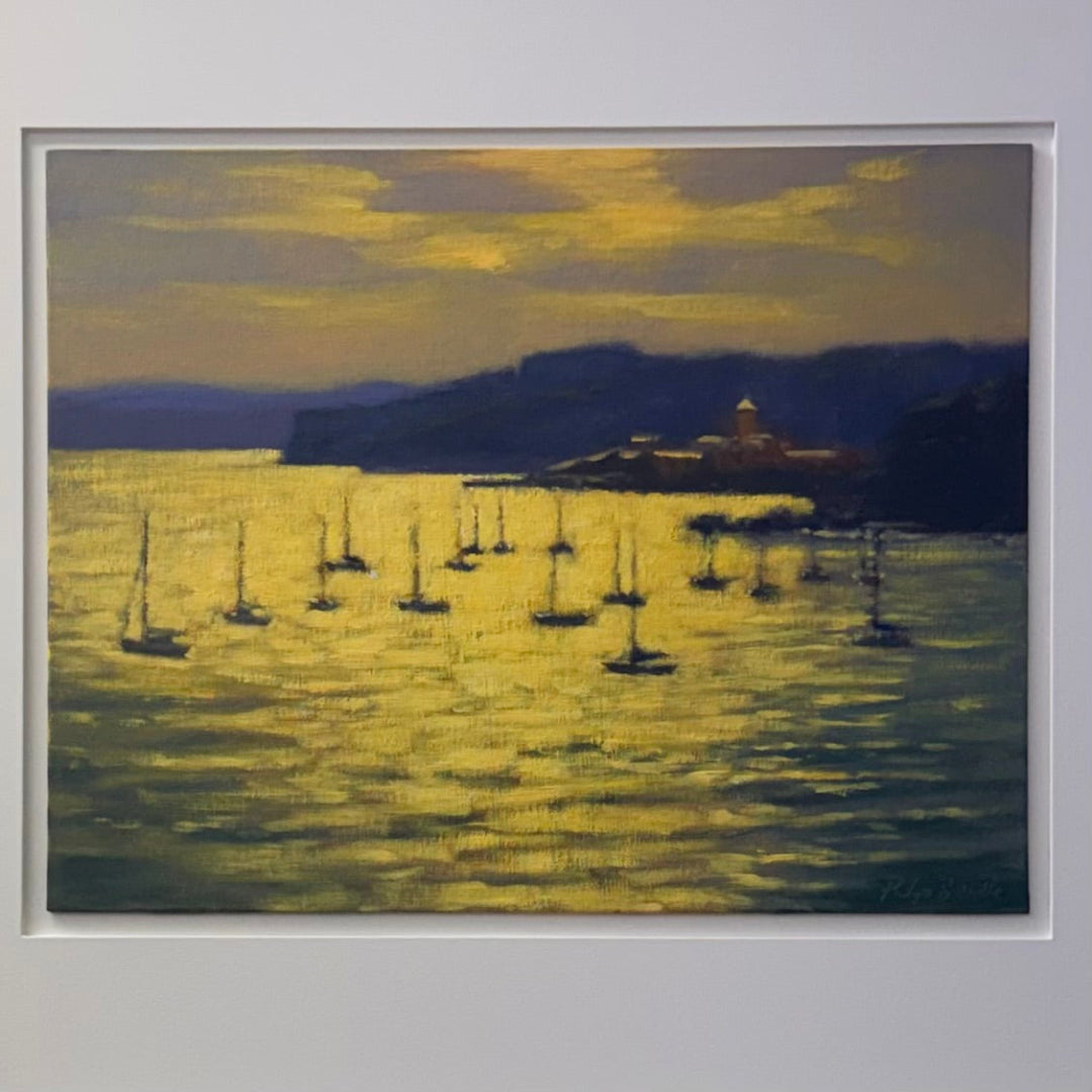 Framed artwork of a sunset over a body of water with sailboats and a mountain.
