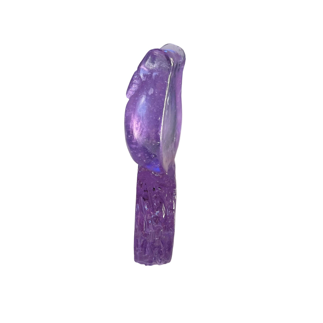 Side view of an amethyst coloured glass owl sculpture on a white surface