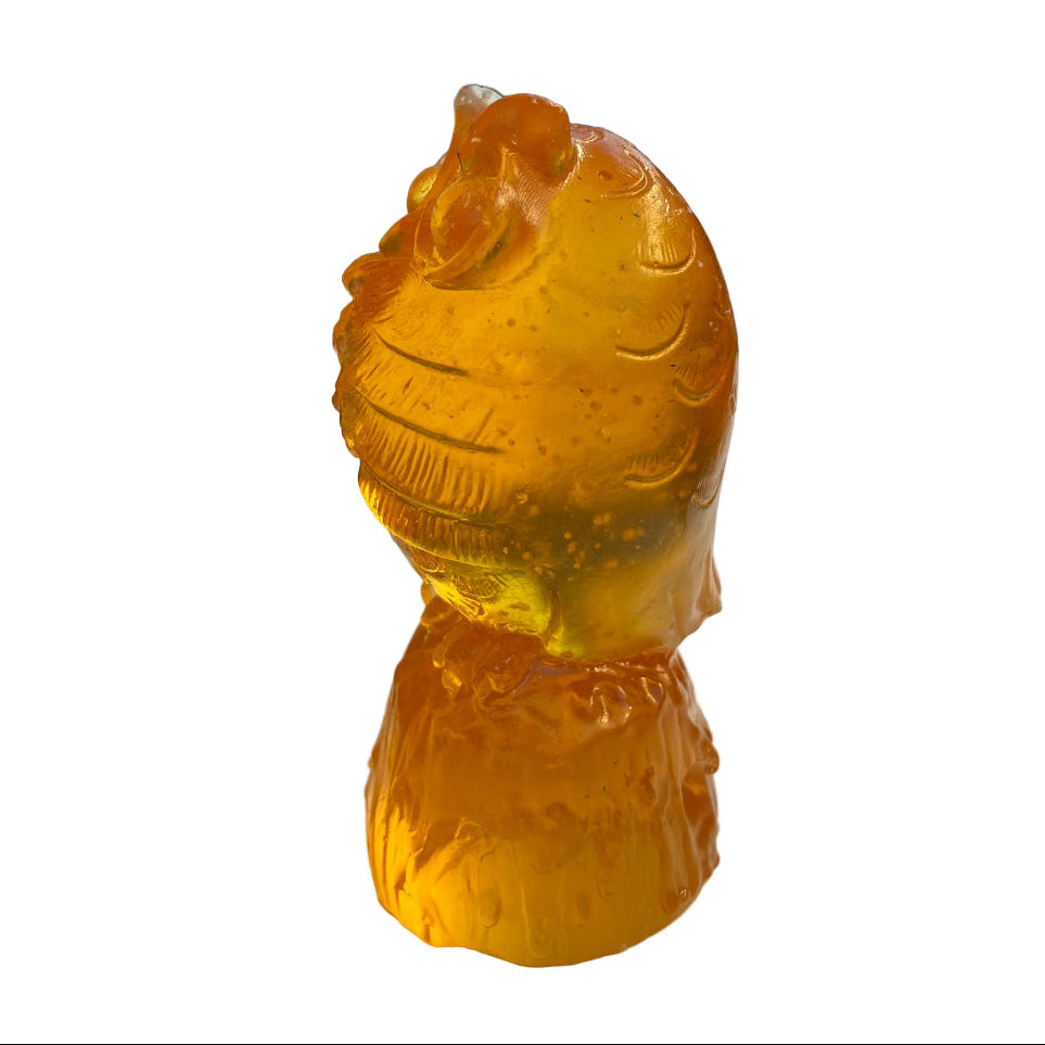 Side view of an orange owl glass sculpture on a white surface