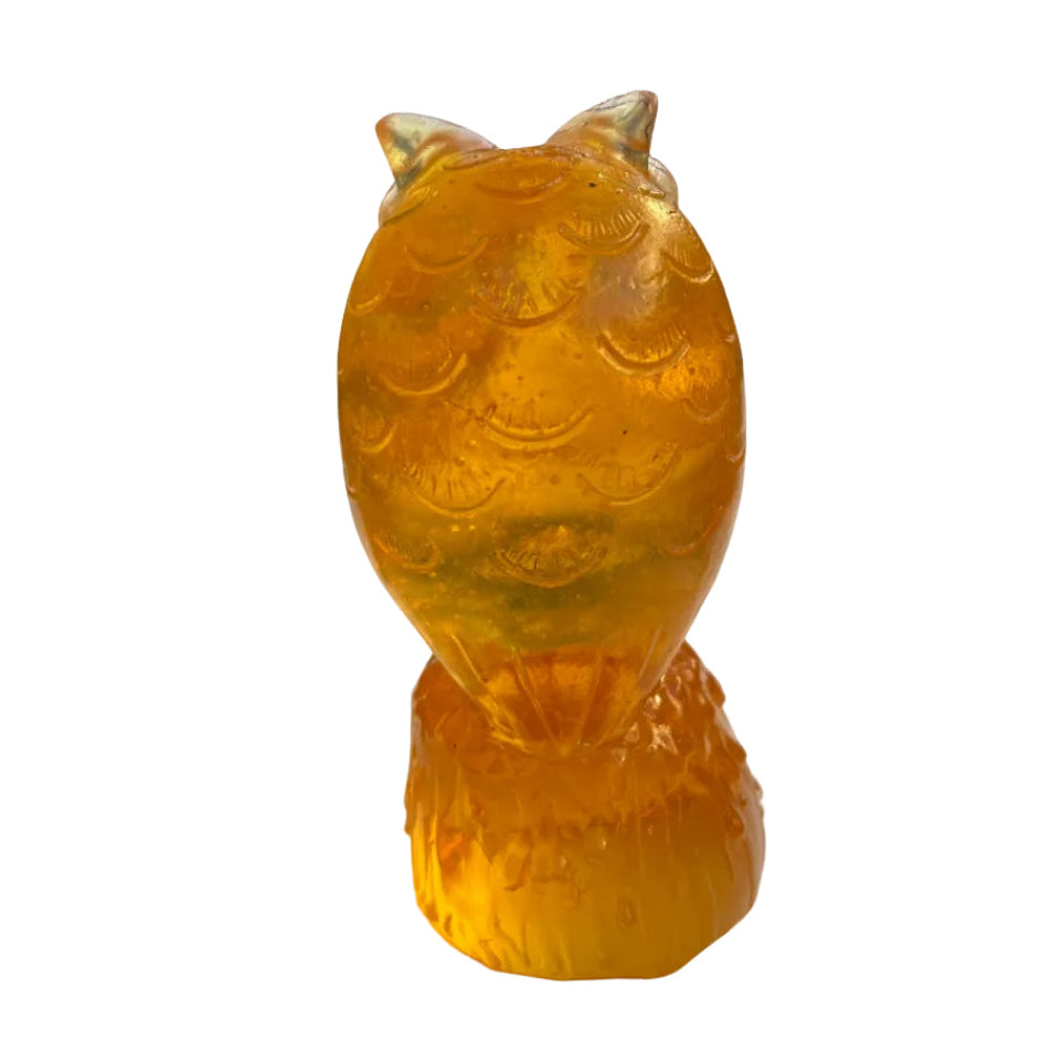 Back view of an orange owl glass sculpture on a white surface