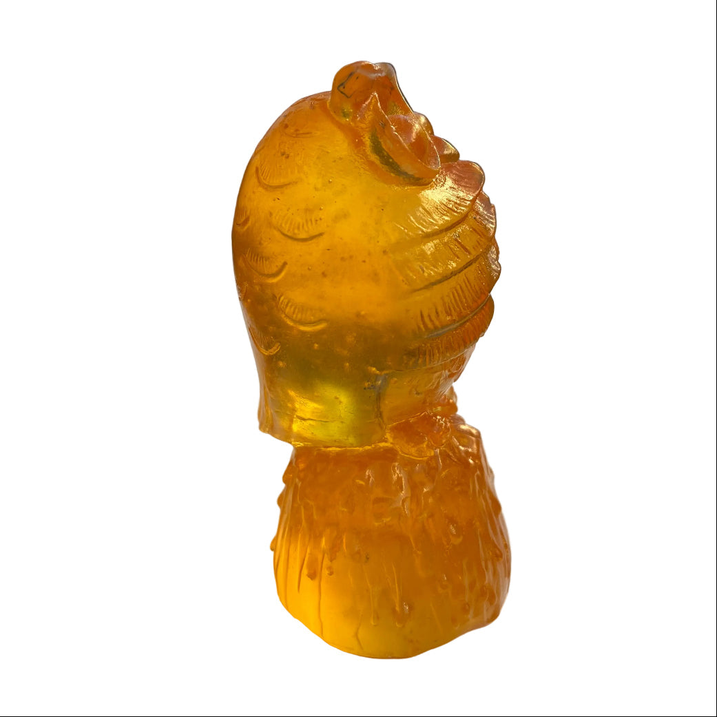 Side view of an orange owl glass sculpture on a white surface