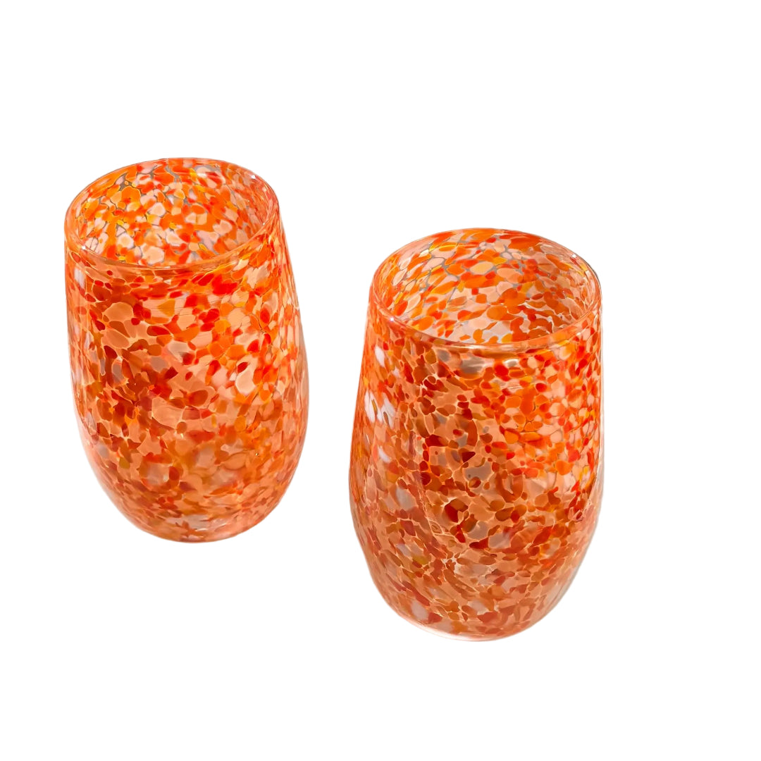 Two orange and white speckled tumblers on a white surface.