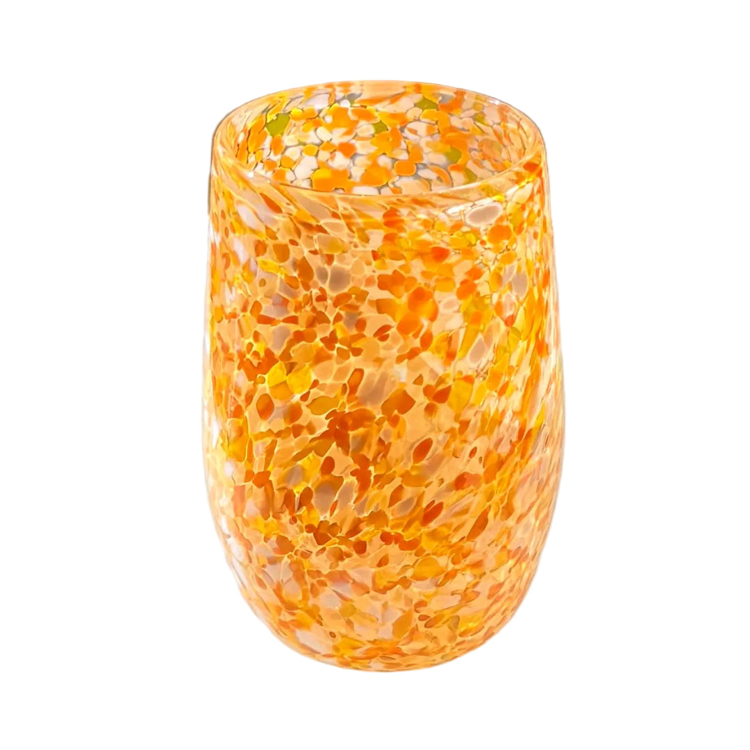 Decorative glass tumbler with yellow, orange and white speckled pattern on a white background