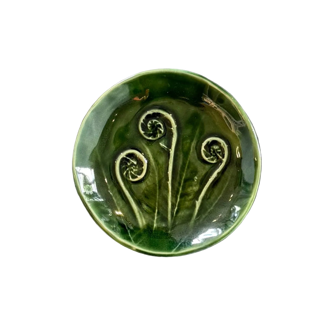 Green ceramic dish with 3 koru pattern on a white background