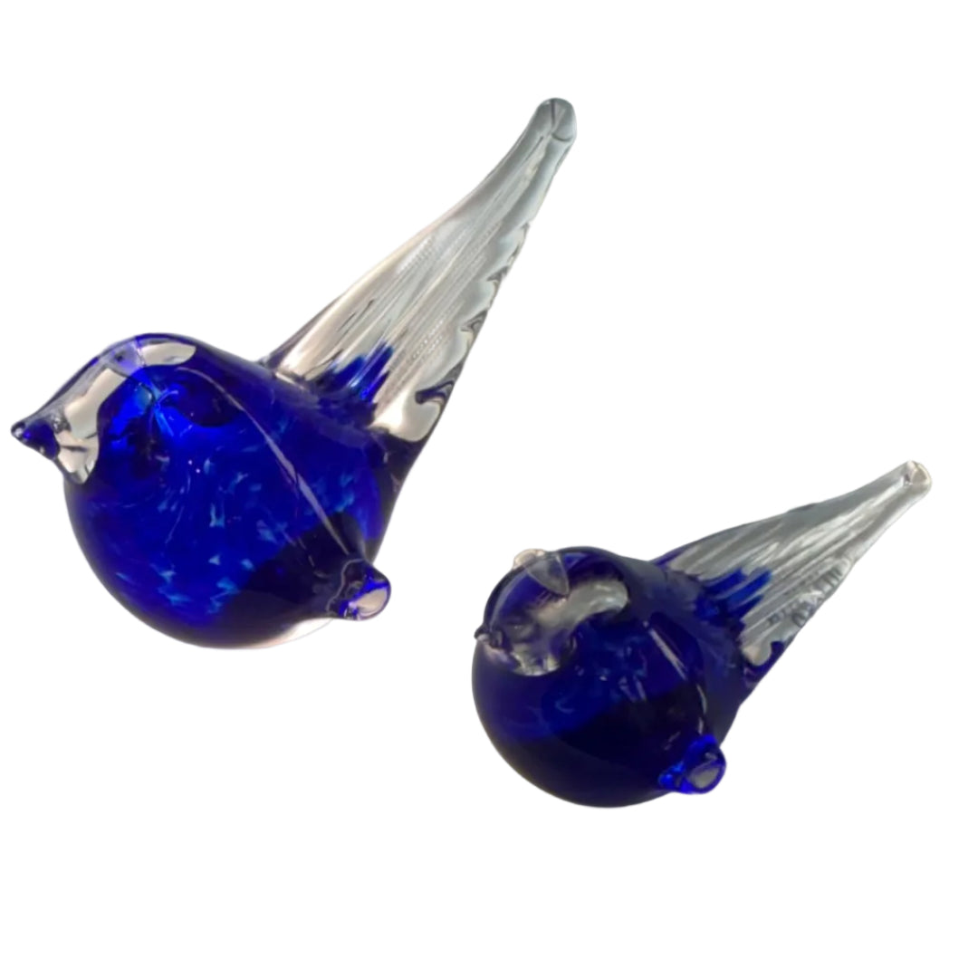 Two blue glass birds on a white surface