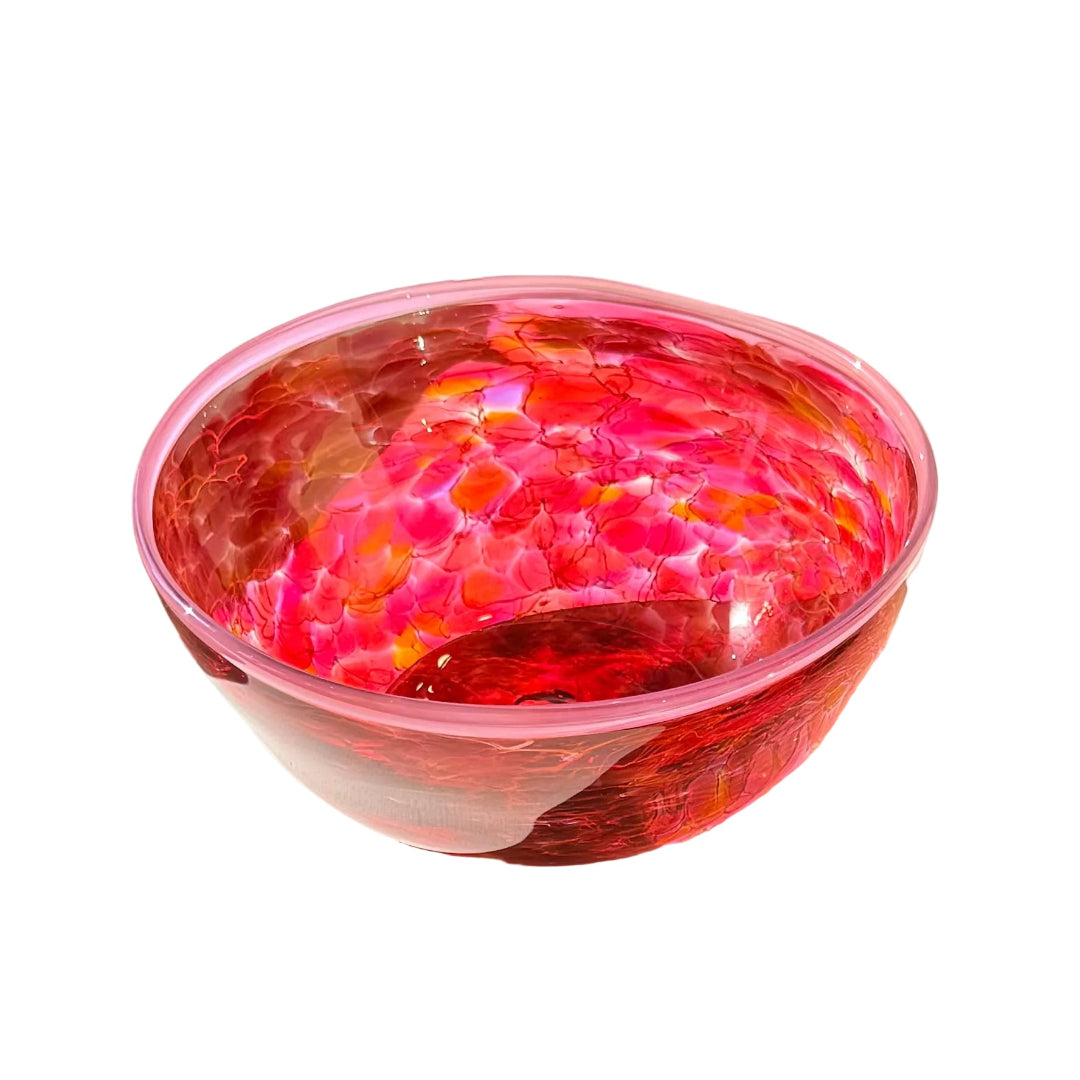 Pink, red and orange marbled glass bowl on a white surface