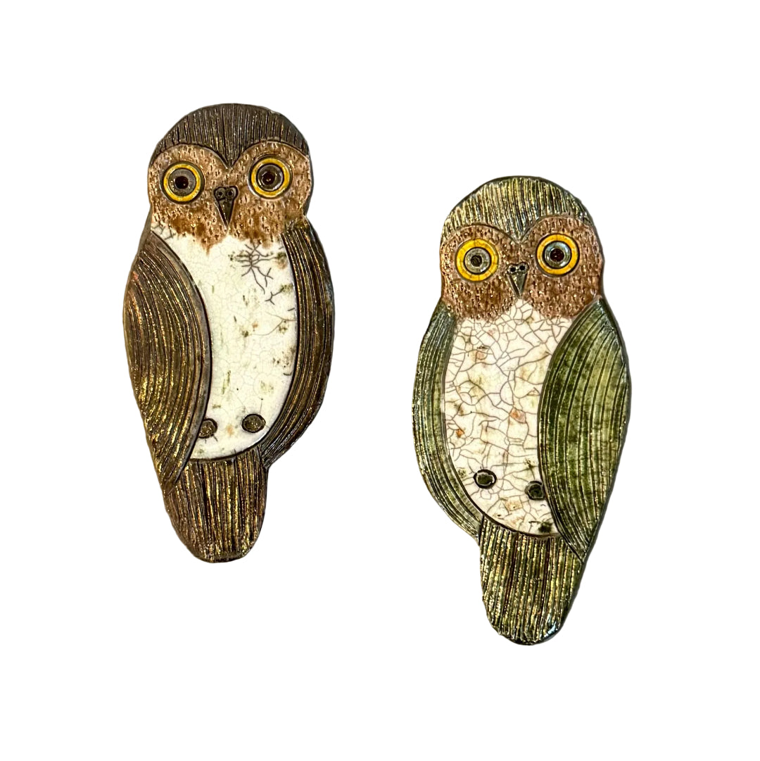 Two raku fired ceramic Morepork shaped wall tiles on a white background