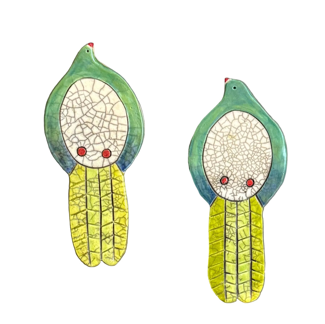 Two colourful ceramic Kereru shaped wall tiles on a white background