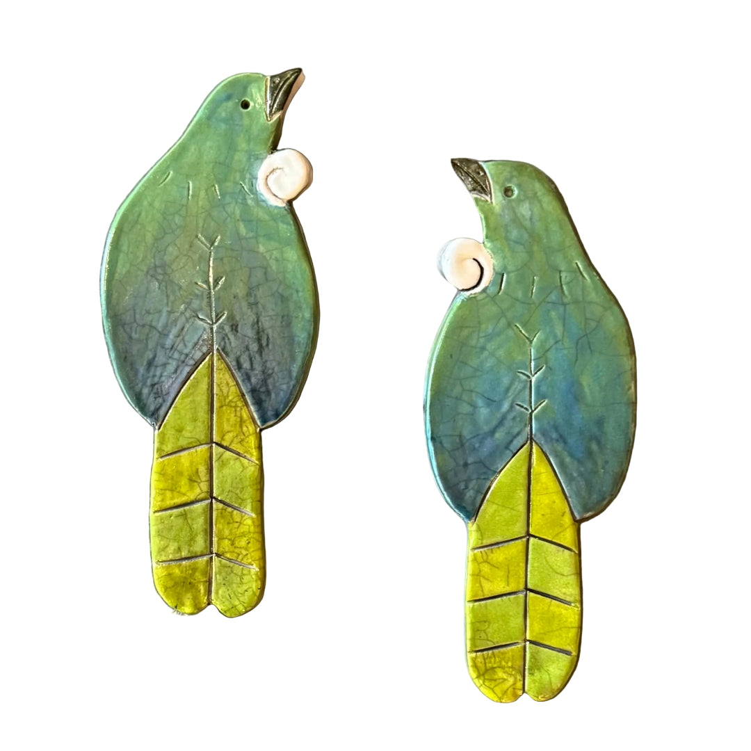 Two colourful ceramic Tui shaped wall tiles on a white background