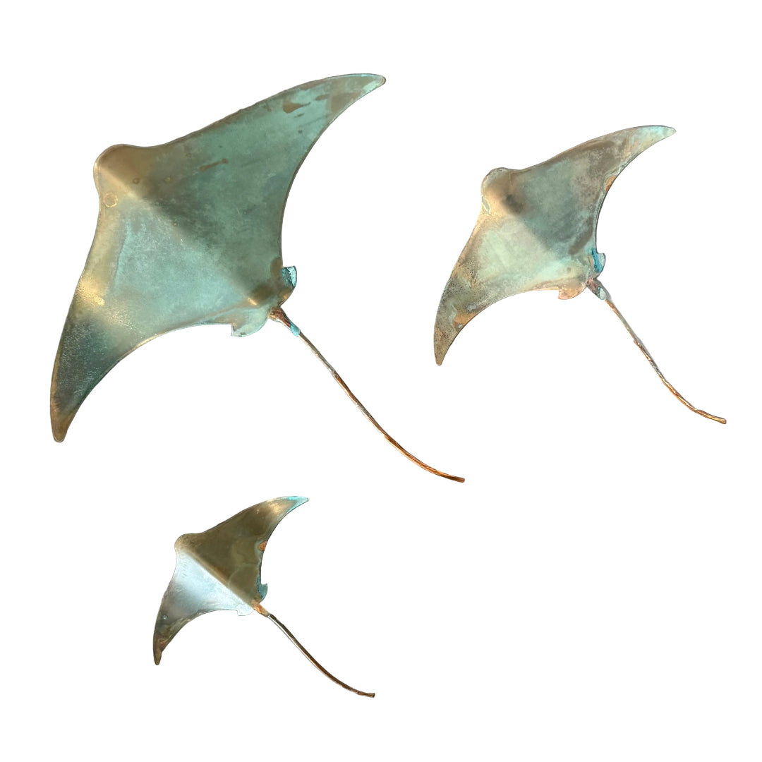 Three copper stingray wall sculptures on a white backgound
