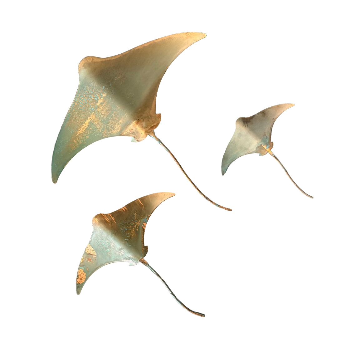 Three copper stingray wall sculptures on a white background