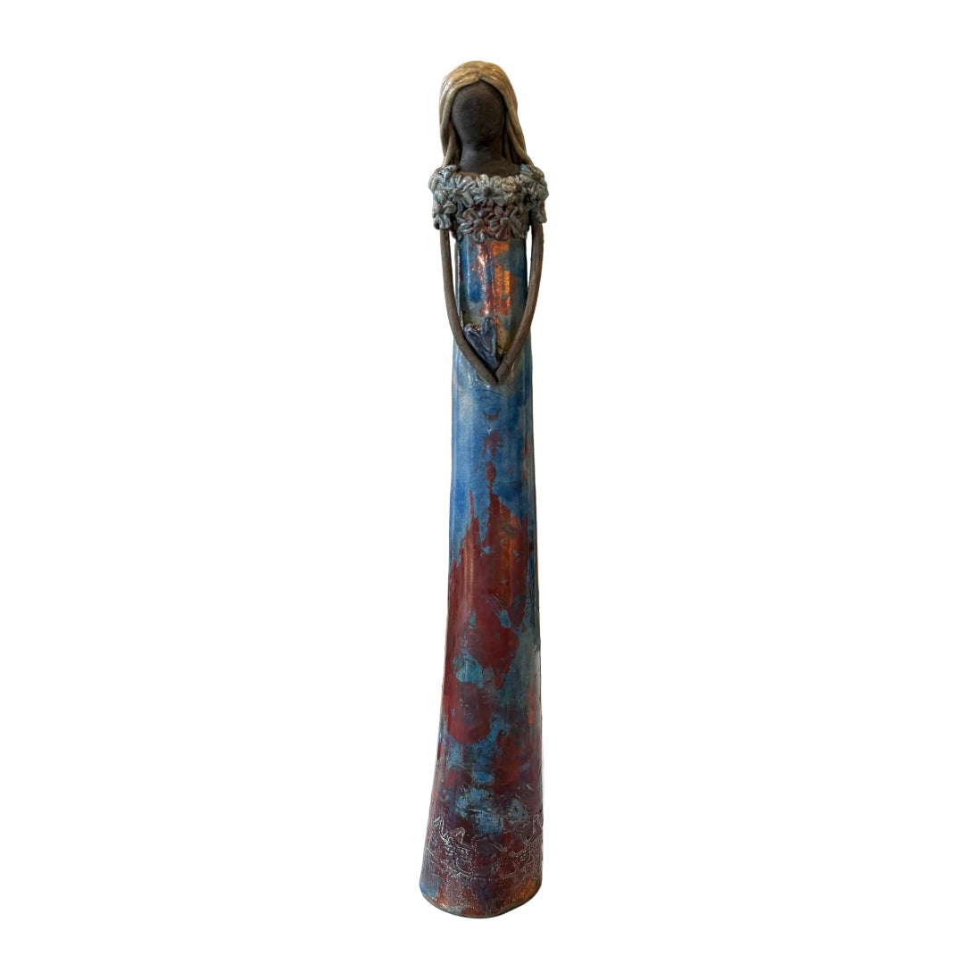 A tall decorative figurine of a woman with a dark head and long blue, teal, and rust-colored body.