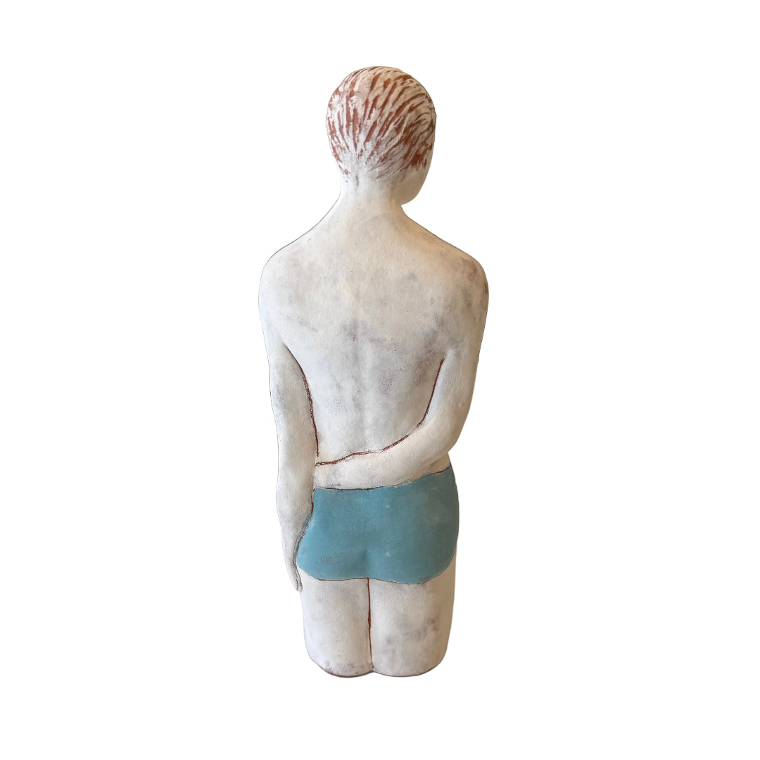 Back view of a ceramic male Swimmer in blue trunks on a white background.