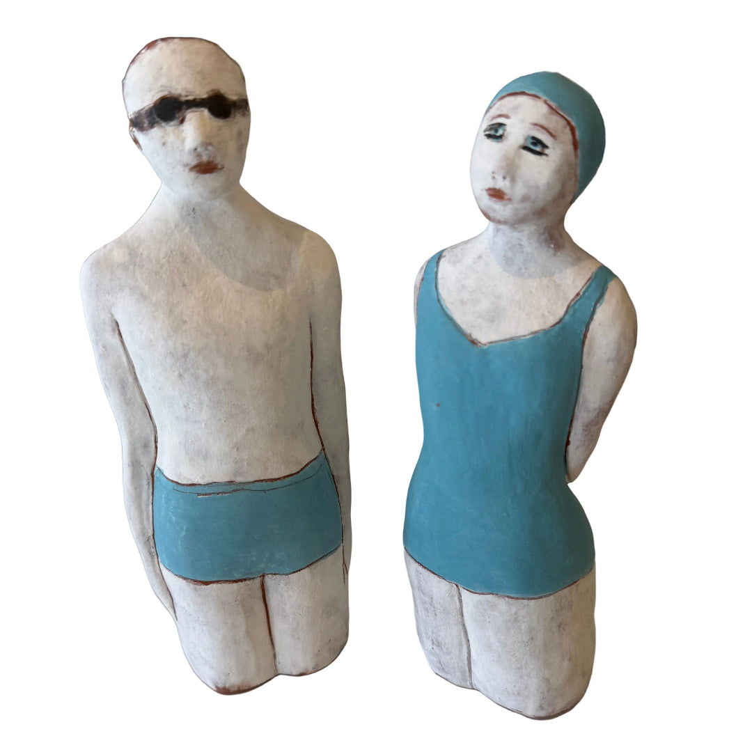 Two ceramic figures, one male and one female, wearing swimsuits on a white background.
