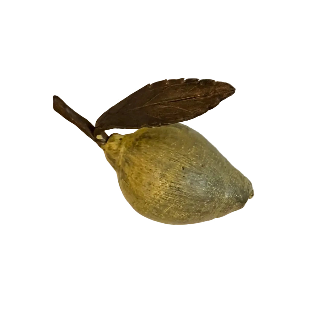 Miniature yellow painted cast bronze lemon with a leaf on a white background
