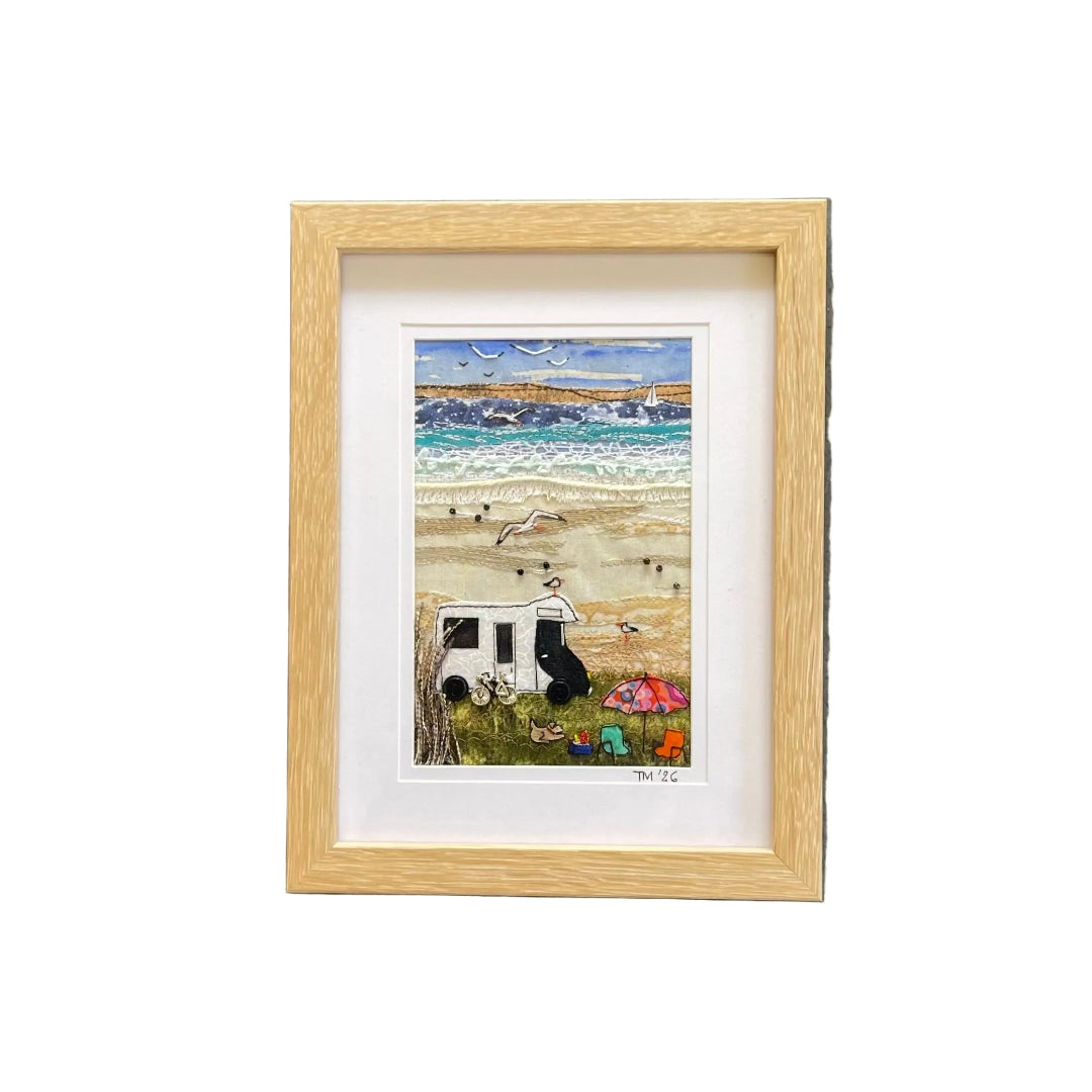 Framed miniature landscape textile artwork of a beach scene with a white camper van, mounted on a white wall.