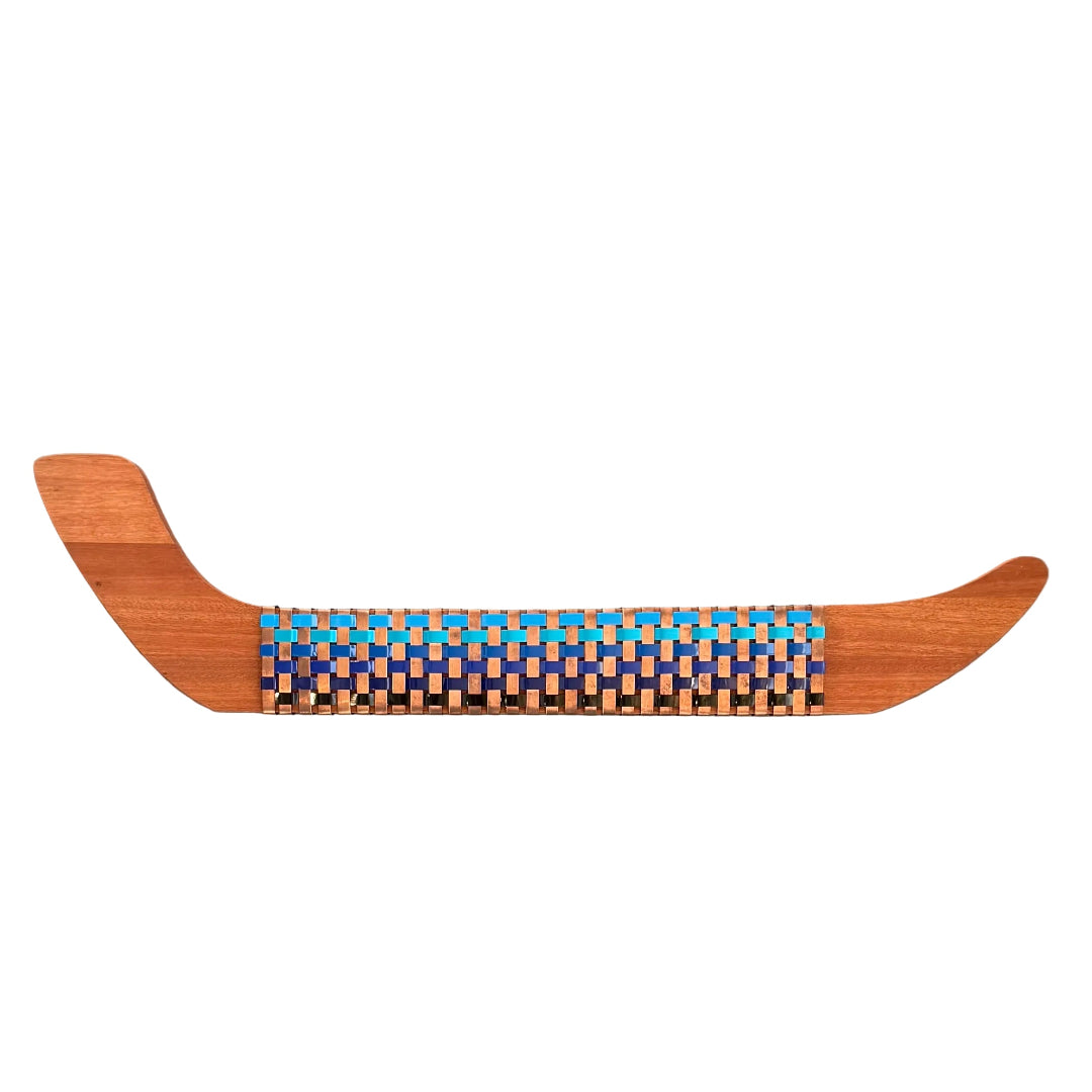 Wooden wall Waka with woven copper, blue and black aluminium pattern on a white background