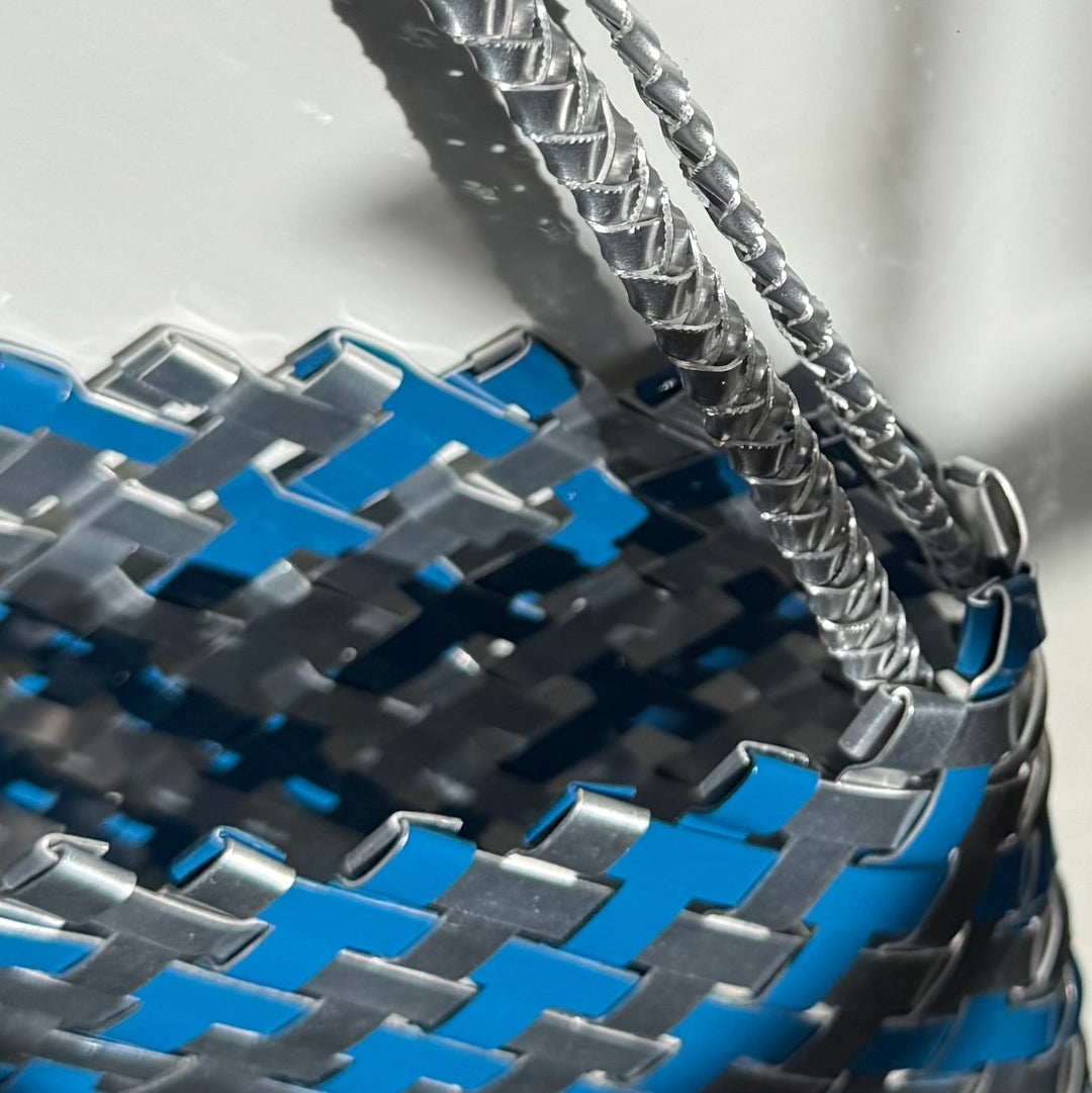 Close-up of a woven basket with blue and silver aluminium pattern on a white background