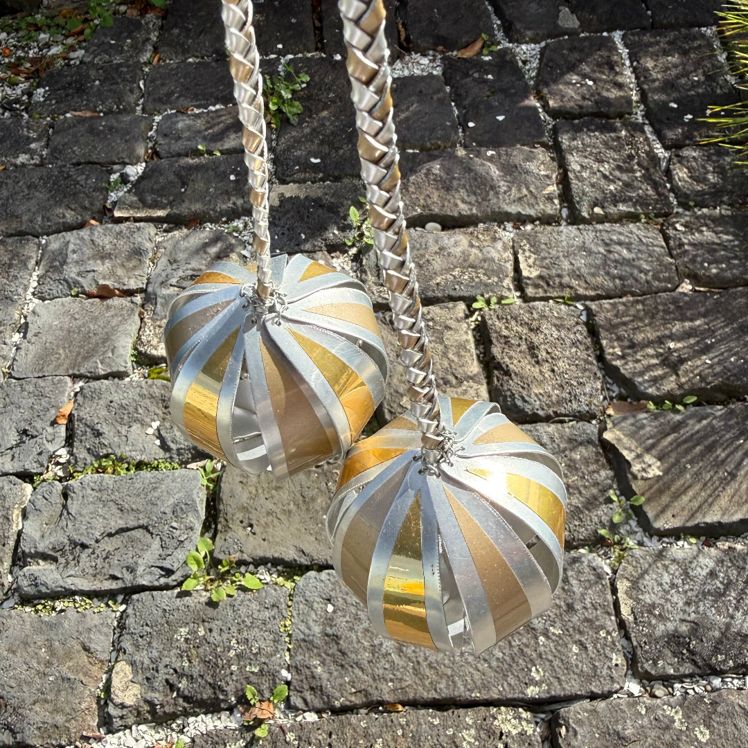 Close up view of a pair of silver & gold aluminium poi on a stone pavement background