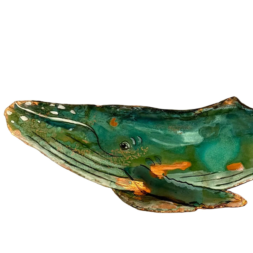 Decorative copper whale wall sculpture on a white surface