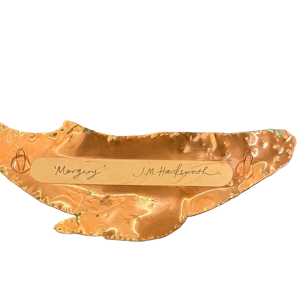 Back of copper whale wall sculpture with 'Margery' and signed 'J.M. Hawksworth' on a white background