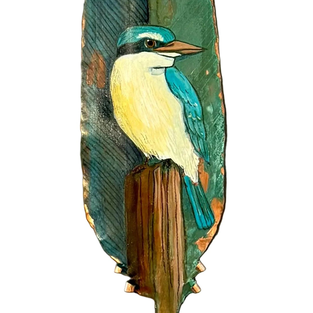 Close up of a painted copper feather with a kingfisher design on a white backgorund