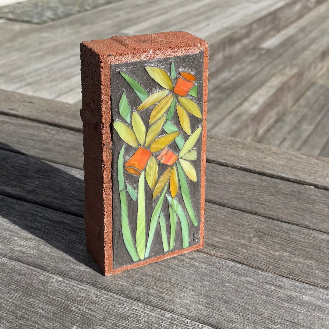 Decorative brick with floral mosaic on a wooden surface