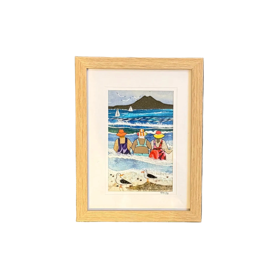 Framed artwork of a beach scene on a white wall