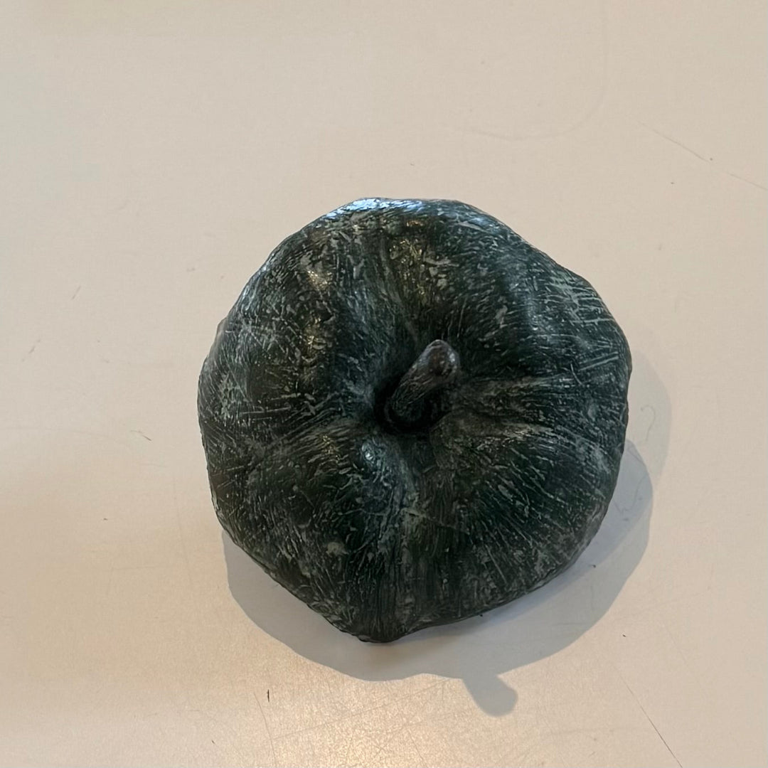 Top of a greenish-brown cast bronze half eaten apple sculpture on a beige background