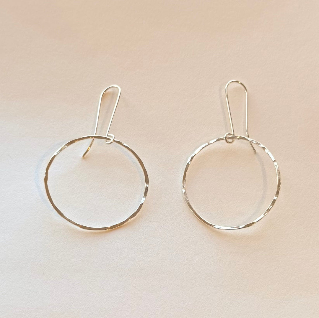 Pair of silver hoop earrings on a beige background
