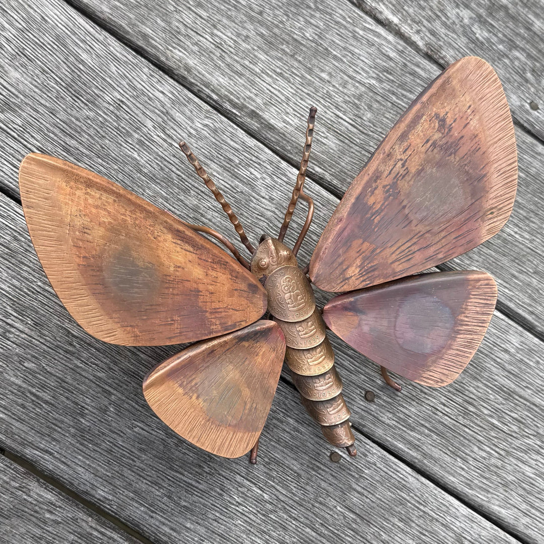 Copper Kawakawa Looper Moth sculpture on a wooden surface