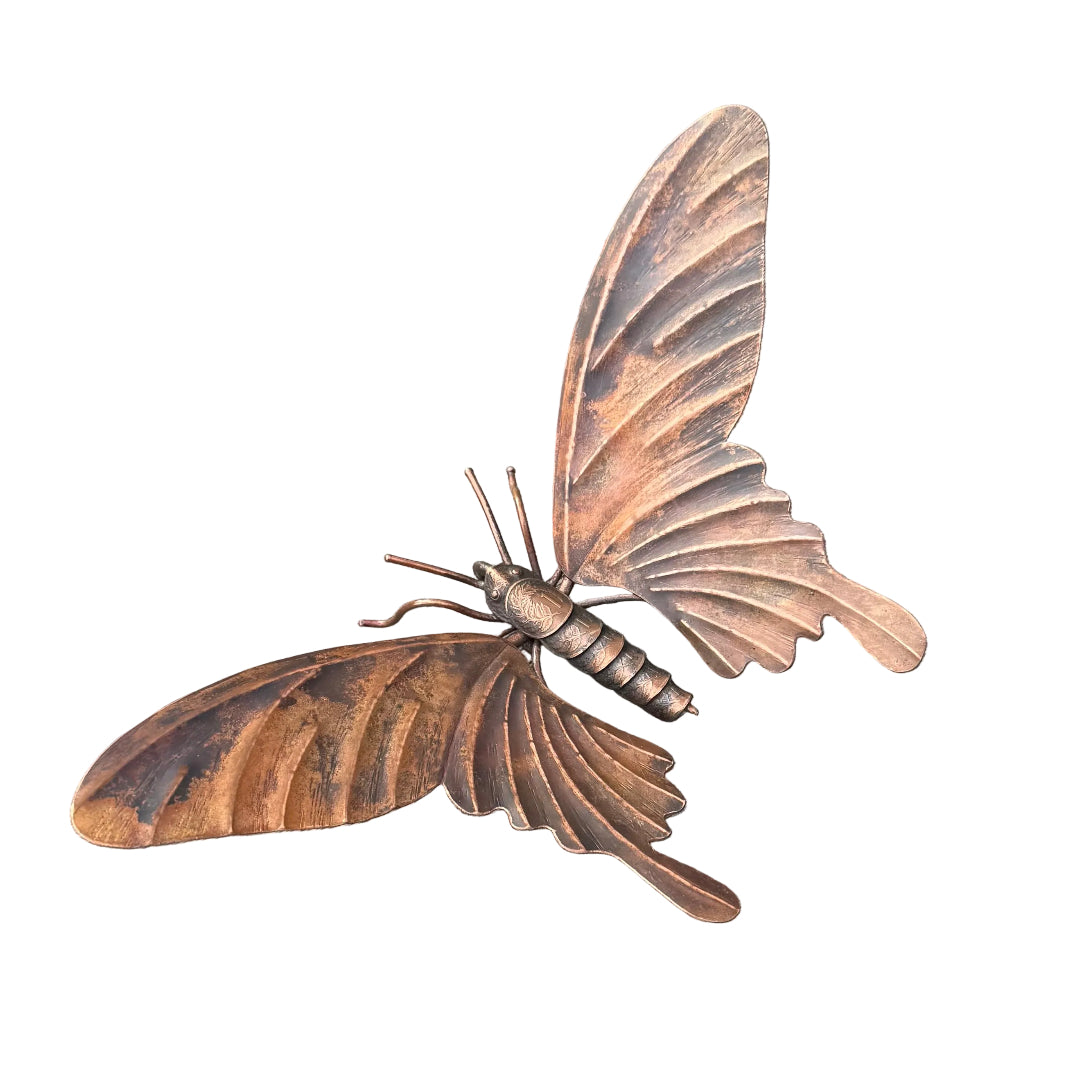 Copper butterfly sculpture with coin body on a white surface