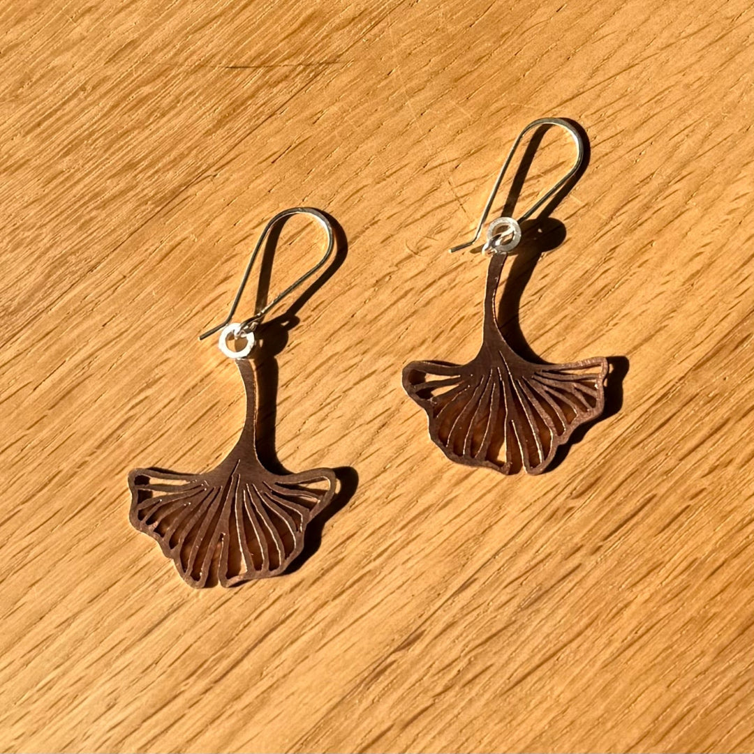 Bronze leaf-shaped earrings on a wooden surface
