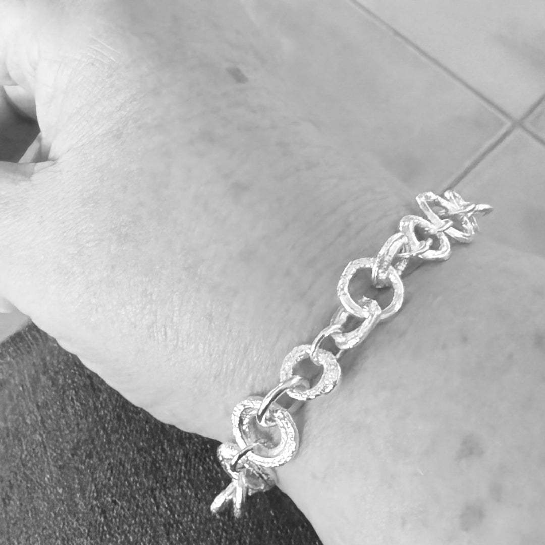 Silver chain bracelet on a wrist with a neutral background