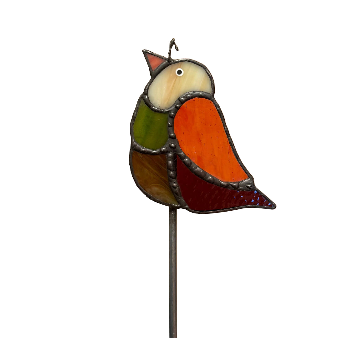 A stained glass bird garden stake featuring a colorful bird design with orange, green, brown, and red glass panels outlined in dark metal, mounted on a thin metal stake against a white background.
