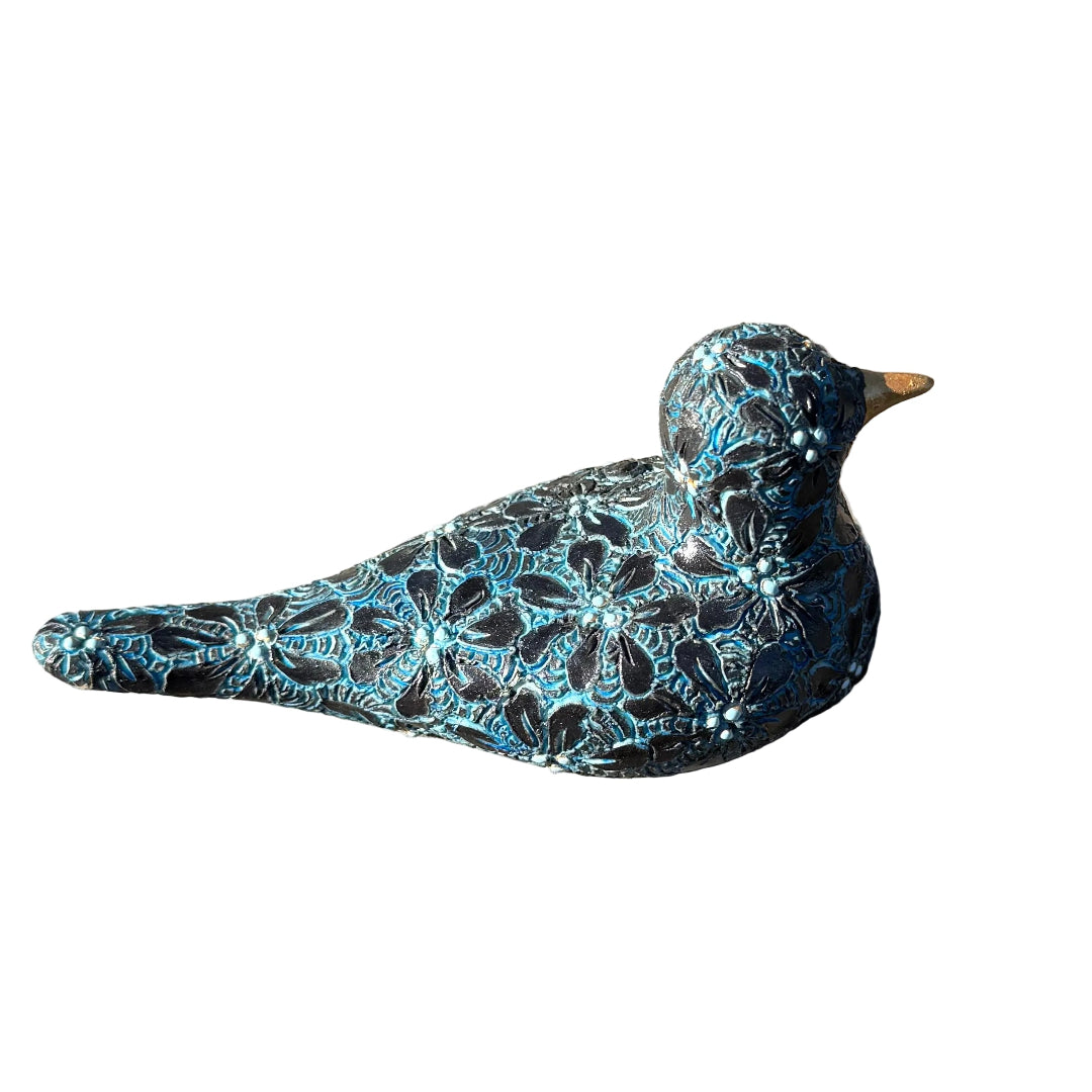 A decorative ceramic bird figurine with a black and turquoise flower pattern and a small gold beak, resting on white background.