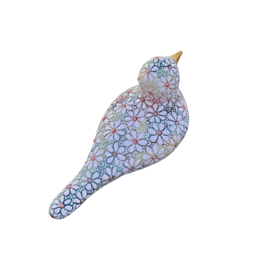 A decorative bird figurine with a colorful floral mosaic pattern on a white base, resting on white background.