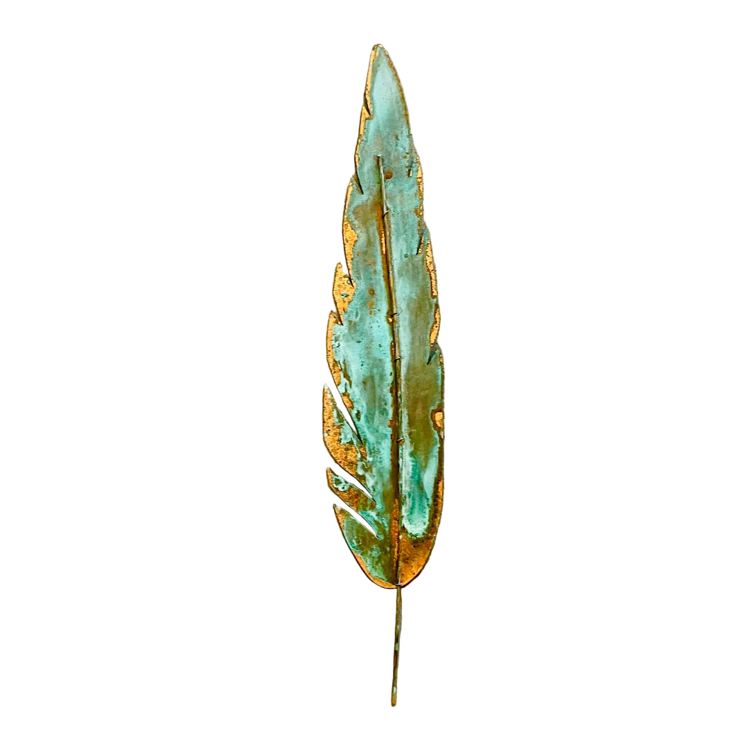 A decorative copper feather wall art piece with a distressed patina showing green verdigris and orange rust-like oxidation, mounted on a white wall.