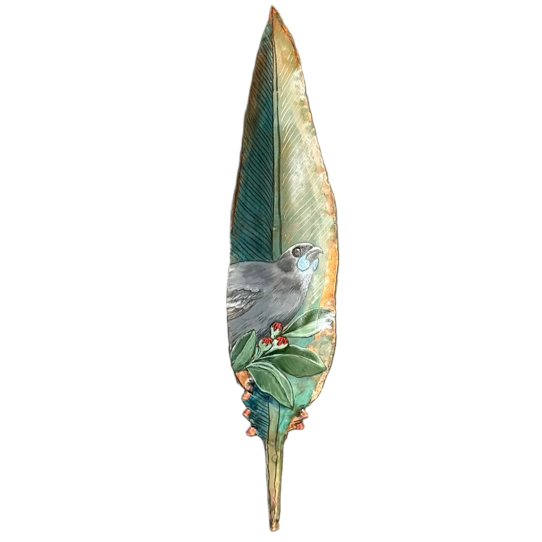 A hand-painted Kokako bird on a copper feather wall sculpture, painted with green, blue, and red details, on a white background.
