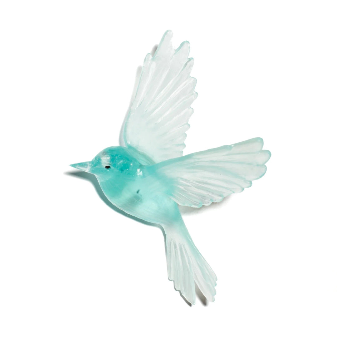 Turquoise bird figurine with transparent wings on a white background
