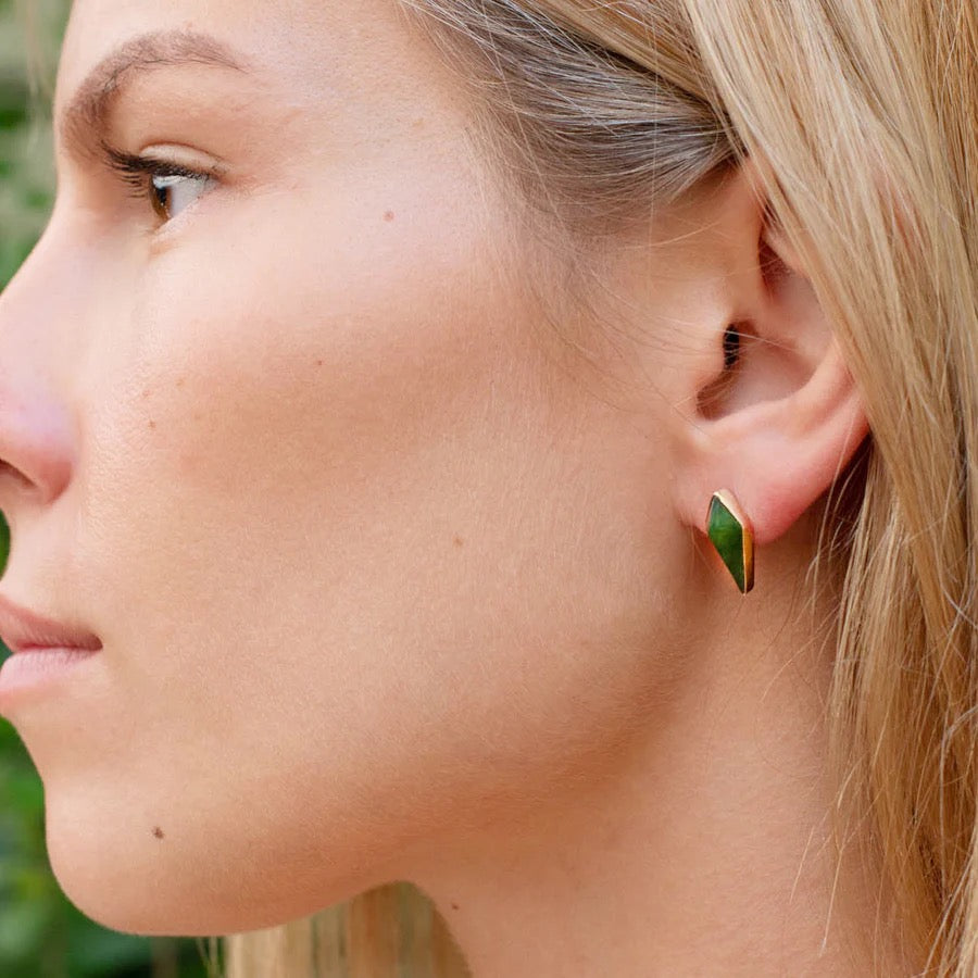 Close-up of a woman wearing a green pounamu and gold earring outdoors