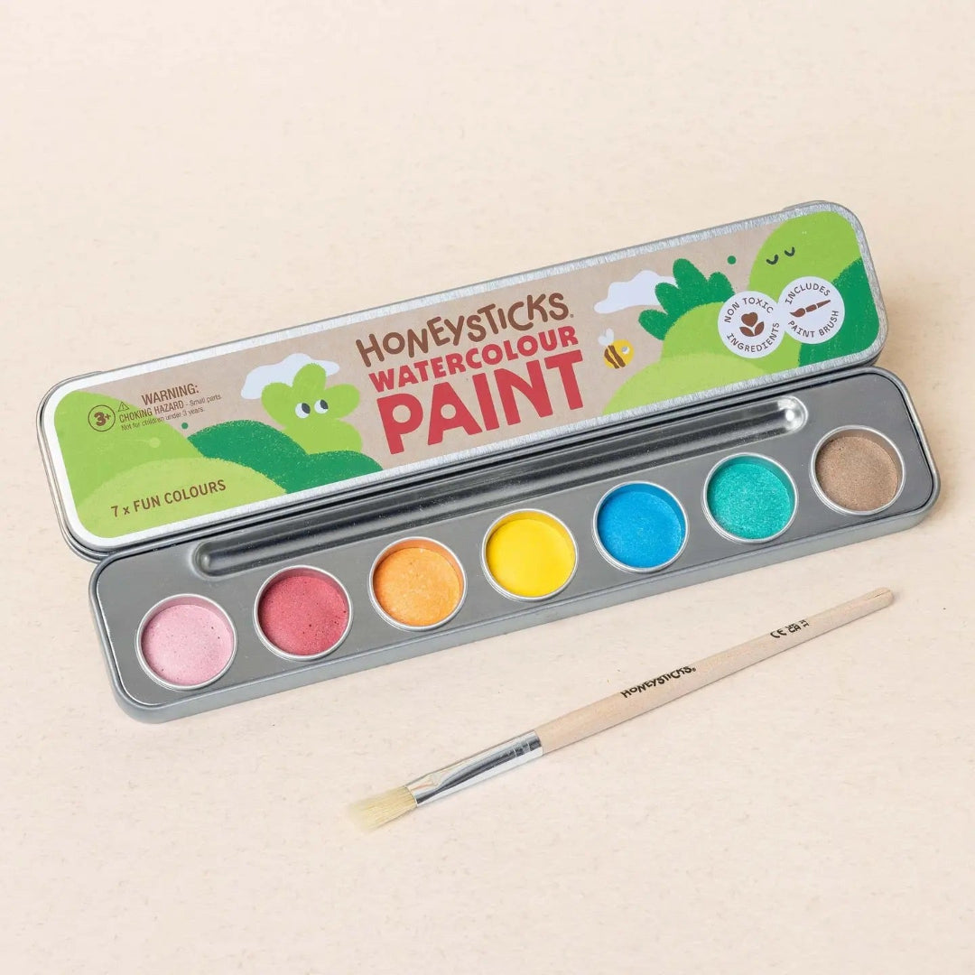 Set of watercolor paint with a brush on a beige background