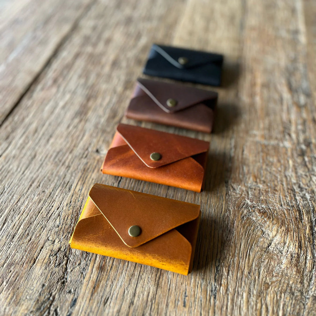 Set of small leather card holders in various colors on a wooden surface
