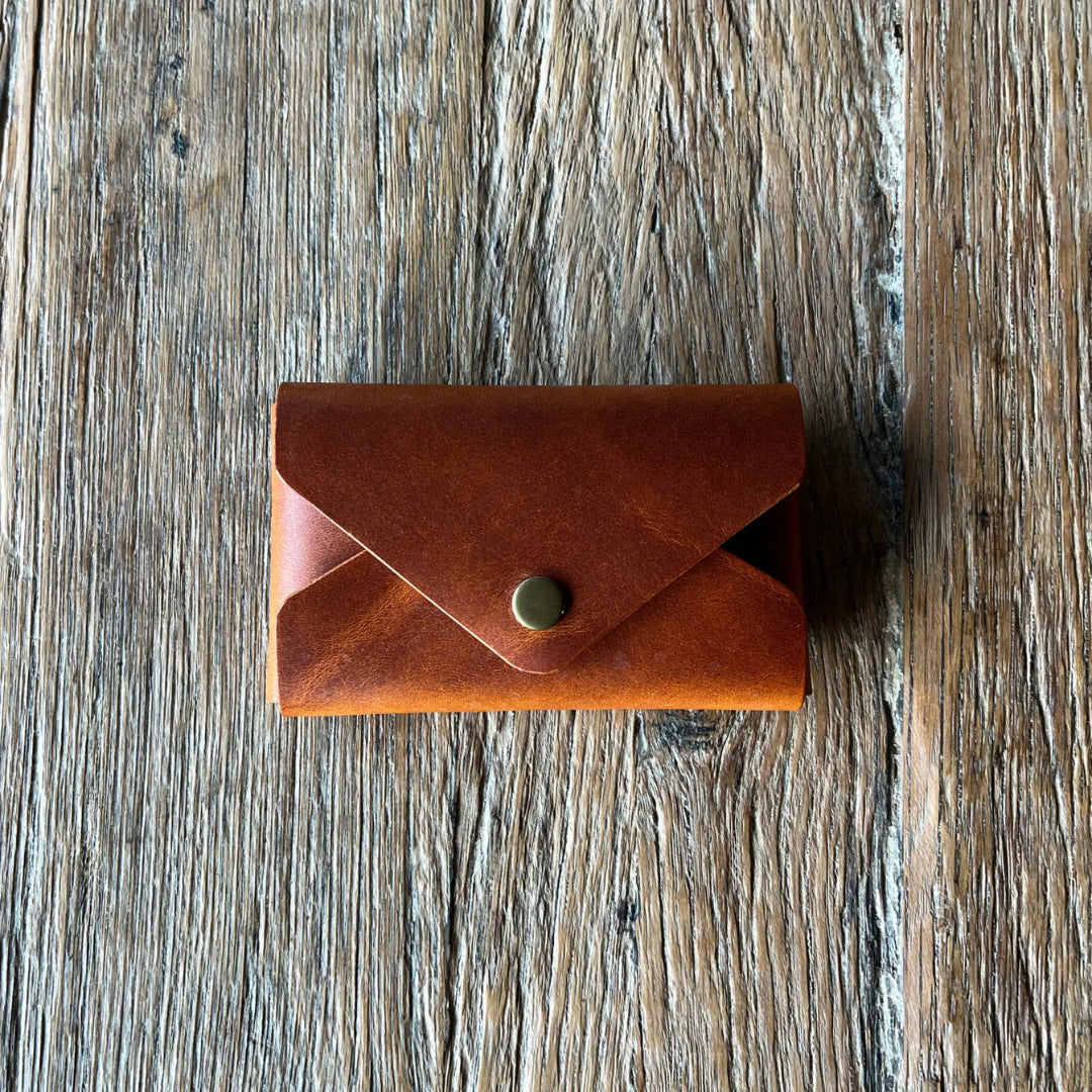 Brown leather wallet with a gold button on a wooden surface