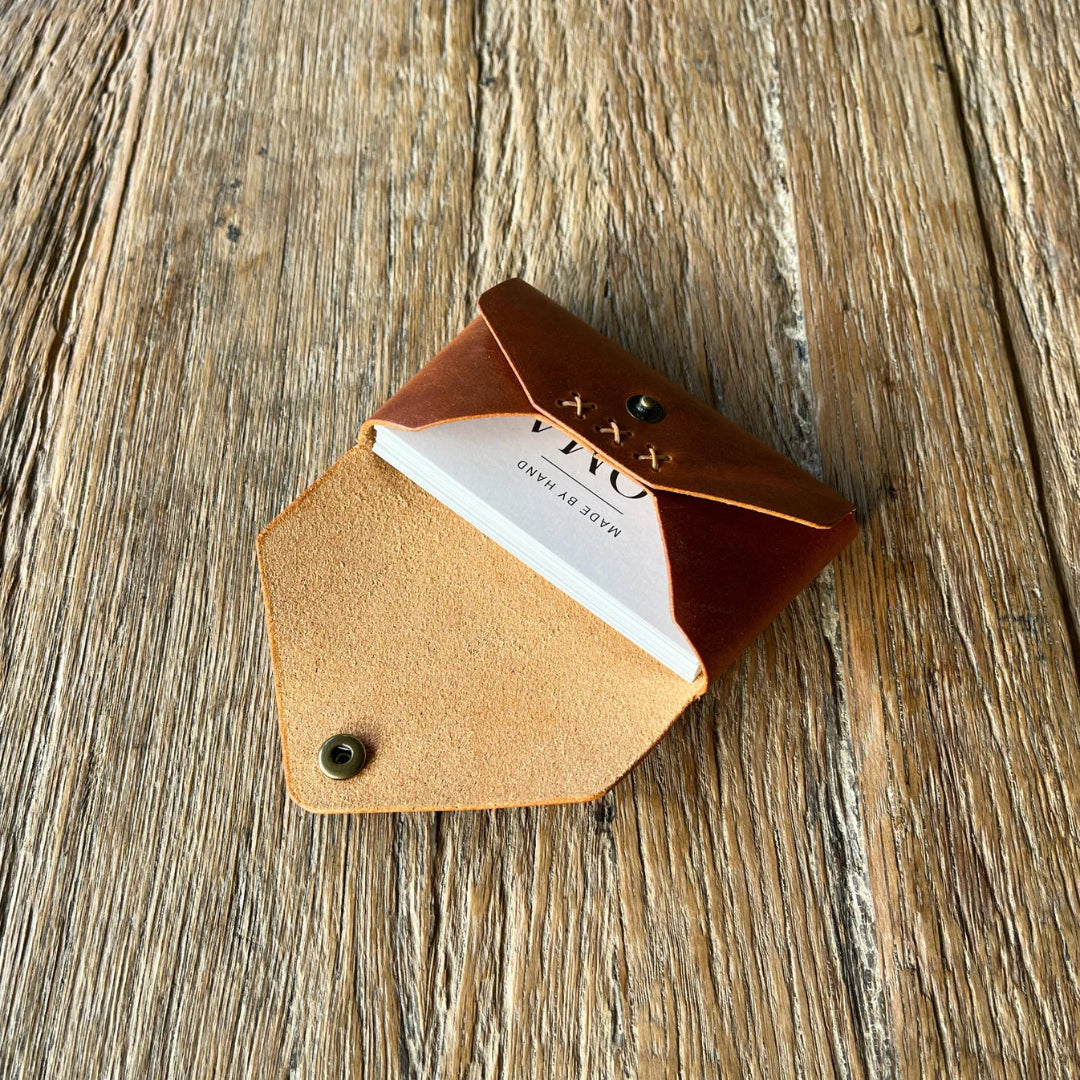 Brown leather cardholder with a white card on a wooden surface