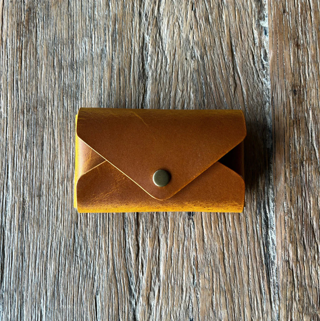 Brown leather wallet with a button on a wooden surface