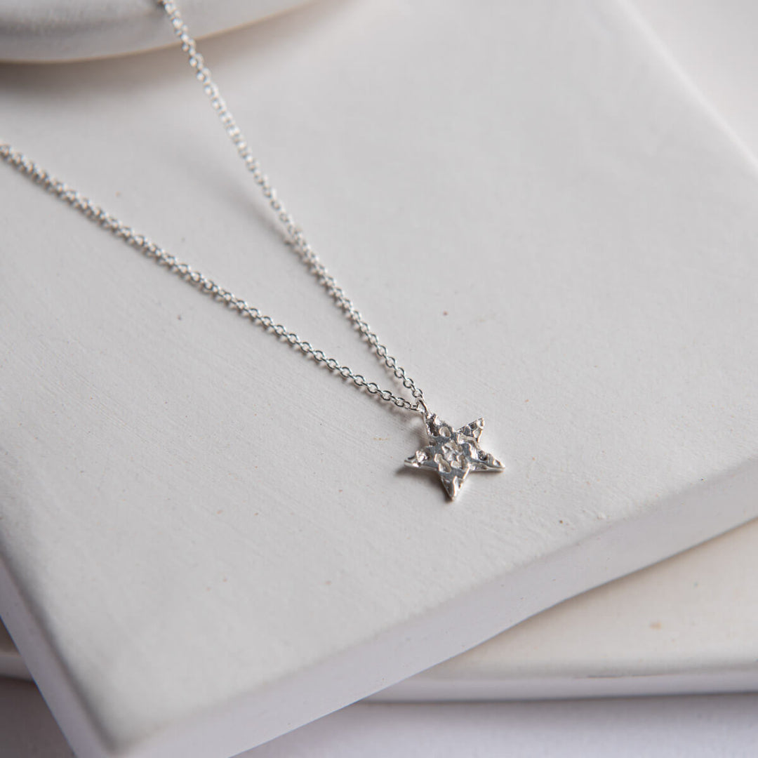 Silver necklace with a star pendant on a white surface