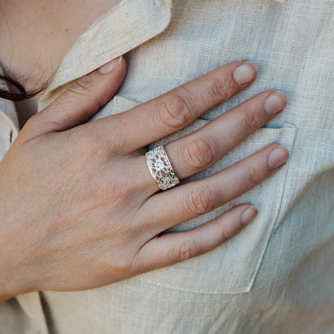 Close-up of a hand wearing a decorative ring on a light fabric background