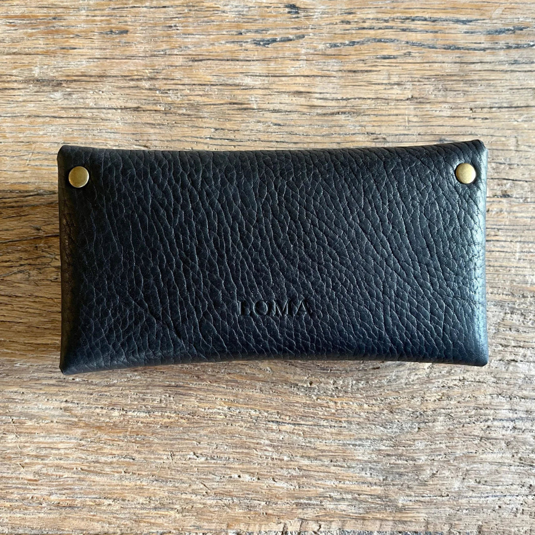 Black leather pouch with gold studs on a wooden surface